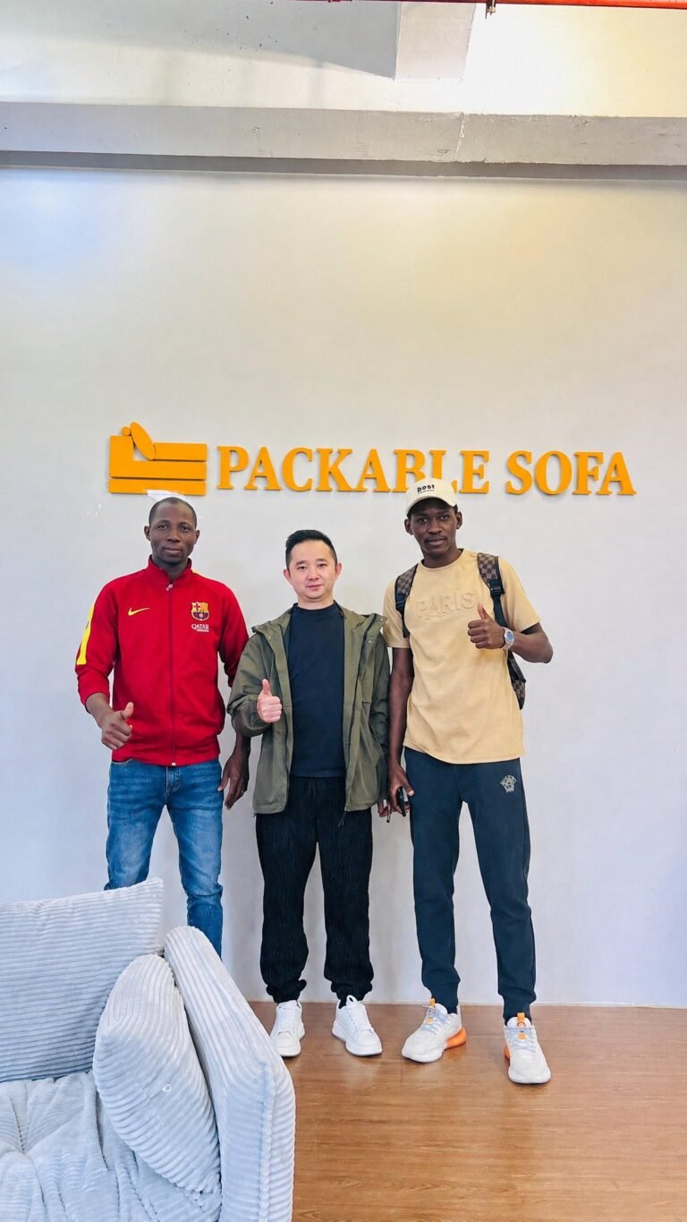 Three people photographed beside a sofa display