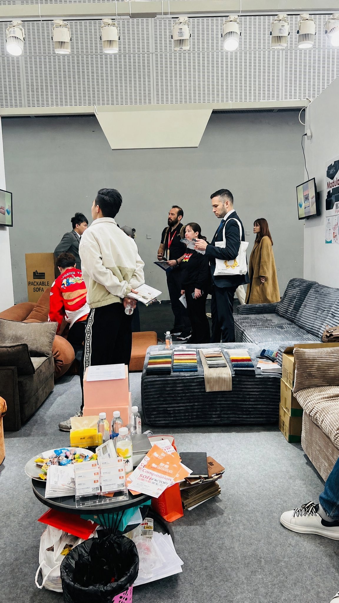 Visitors reviewing sofas and fabric samples at a trade show